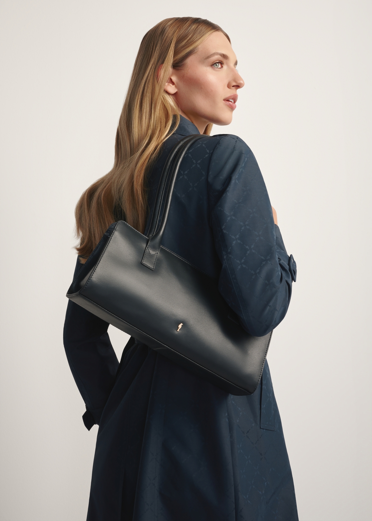 Czarna skórzana podłużna torebka damska TORES-1259-99(W26) - widok produktu po skosie, na modelce, na białym tle. 