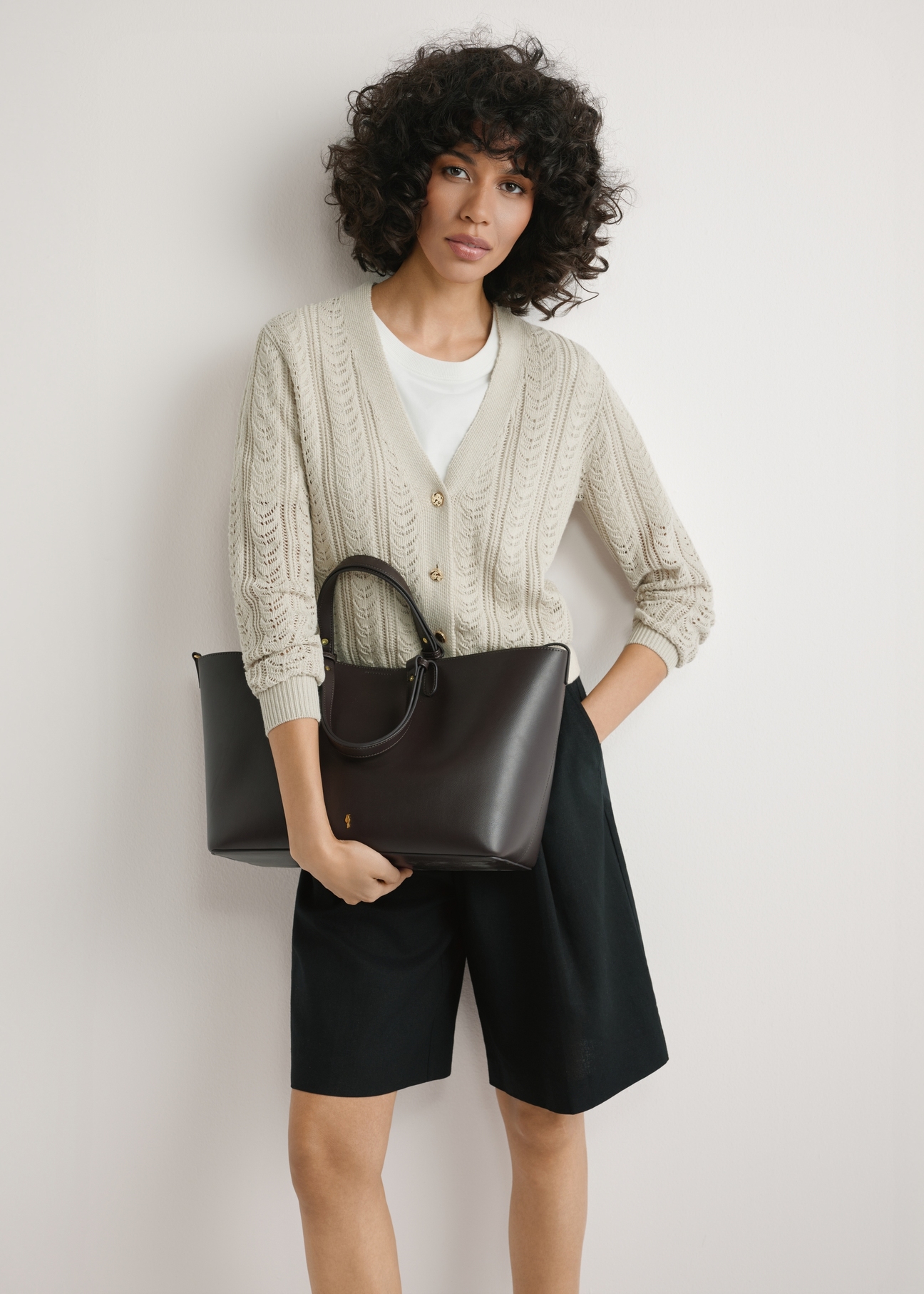 Brązowa damska torebka shopper TOREC-1240-1H(W26),  widok produktu w rękach modelki. Widoczna połowa sylwetki.