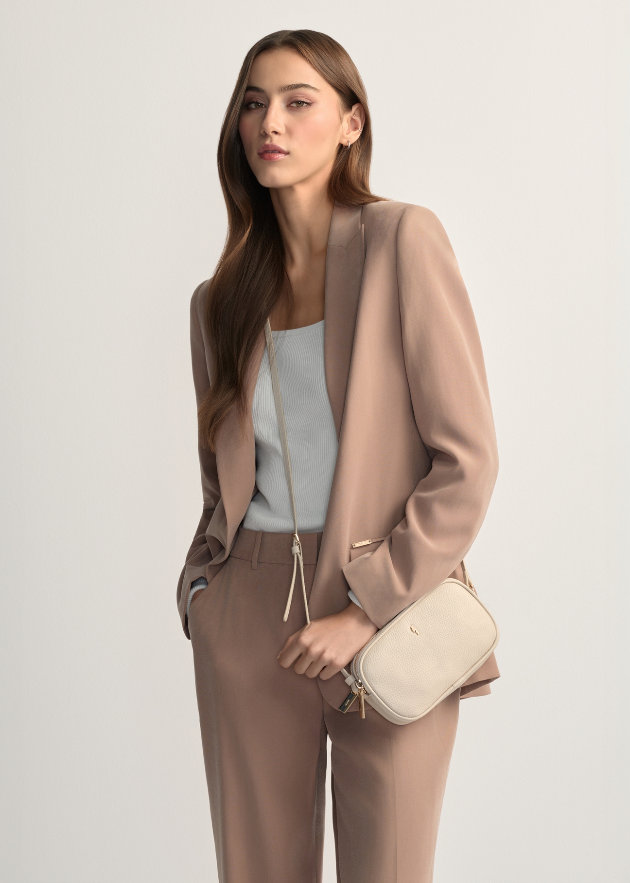 Mała skórzana torebka damska w kolorze kremowym TORES-1152-0B(W26), widok produktu od przodu na modelce, widoczna połowa sylwetki.