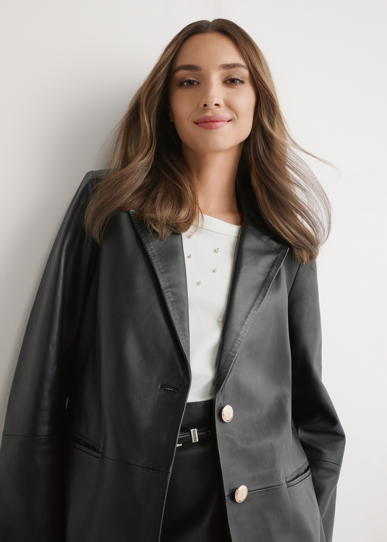 Czarna skórzana marynarka damska KURDS-0606-99(W26) - widok produktu z przodu, na modelu, na jasnym tle. Widoczna połowa sylwetki. 