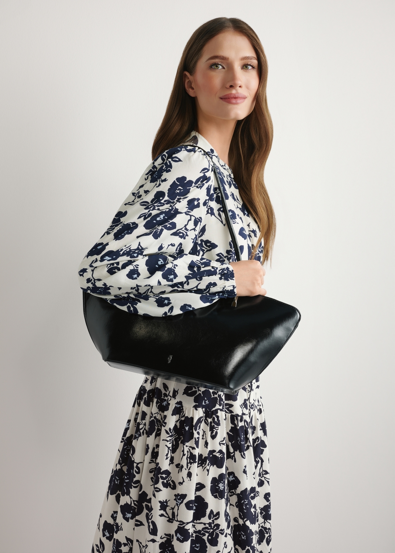 Czarna torebka damska na ramię TOREC-1237-99(W26) - widok produktu z przodu, na modelce, na jasnym tle. Widoczna połowa sylwetki.