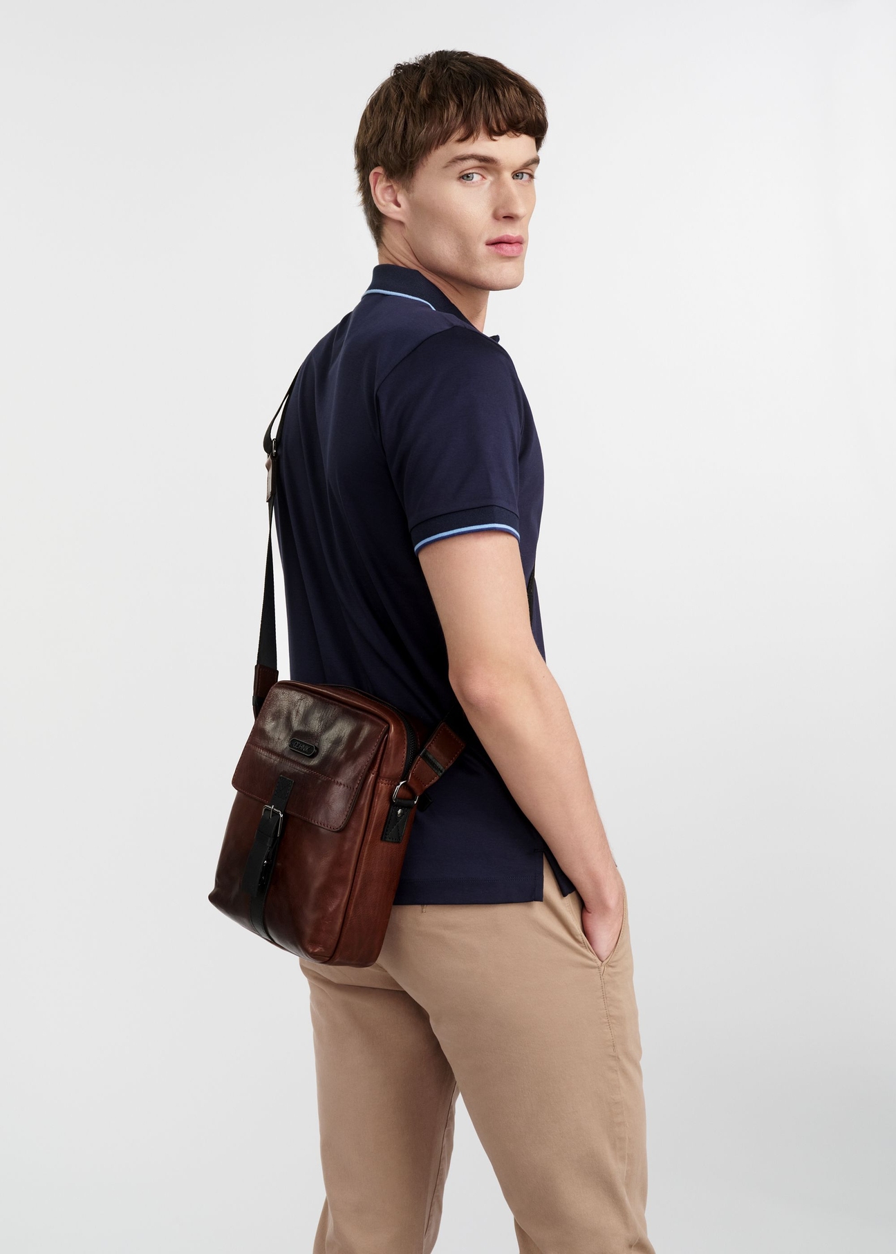 Skórzana brązowa torba męska TORMS-0104-1H(W26), widok produktu z boku na sylwetce modela, na jasnym tle.