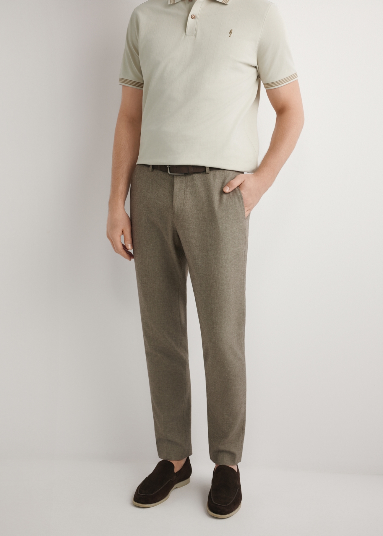 Ciemnobrązowe spodnie garniturowe męskie SPOMT-0098-1I(W26), widok produktu z przodu na modelu. Widoczna połowa sylwetki.