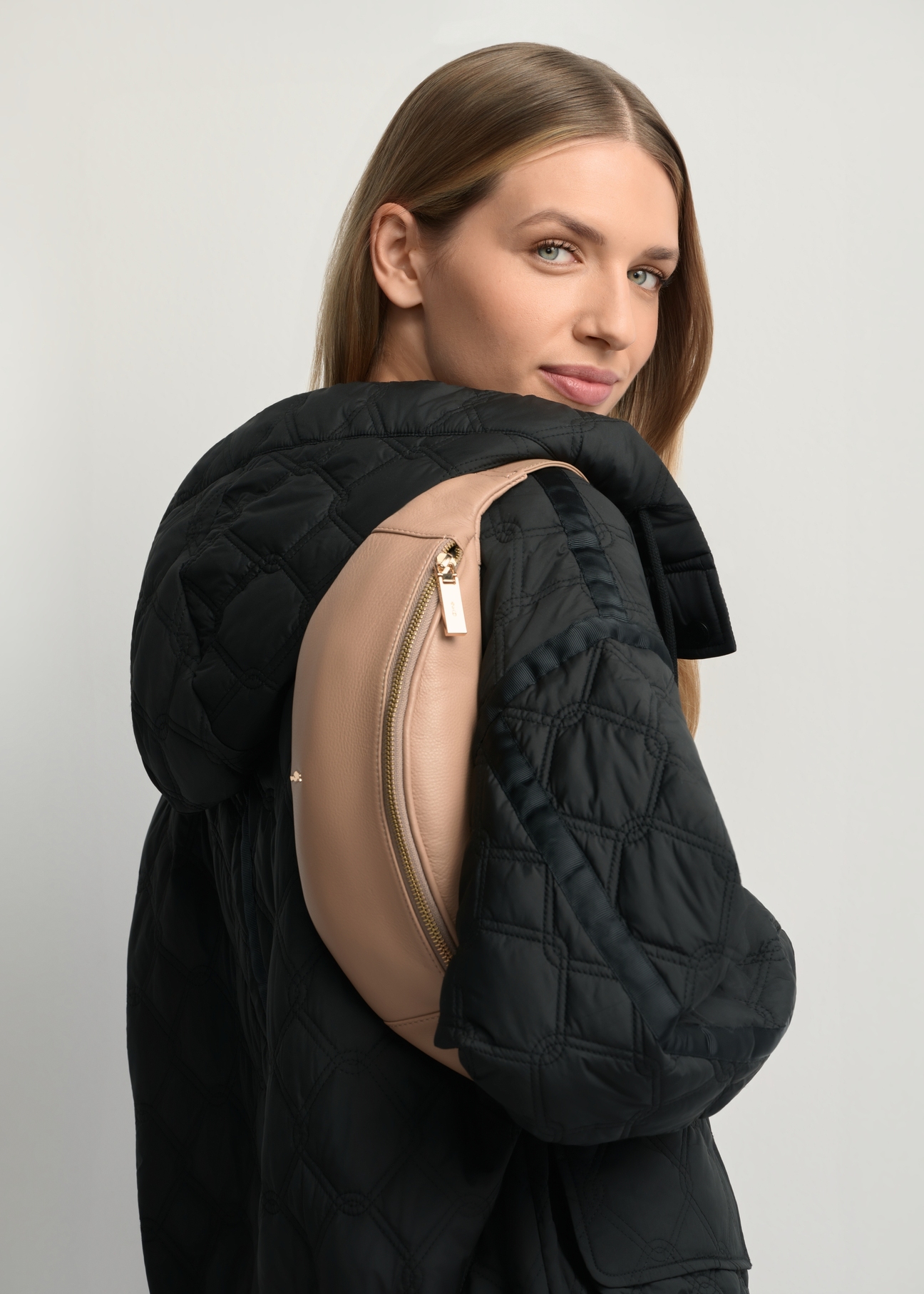 Skórzana beżowa nerka damska TORES-0970F-1B(W26) - widok produktu z boku, na modelce, na jasnym tle. Widoczna połowa sylwetki.