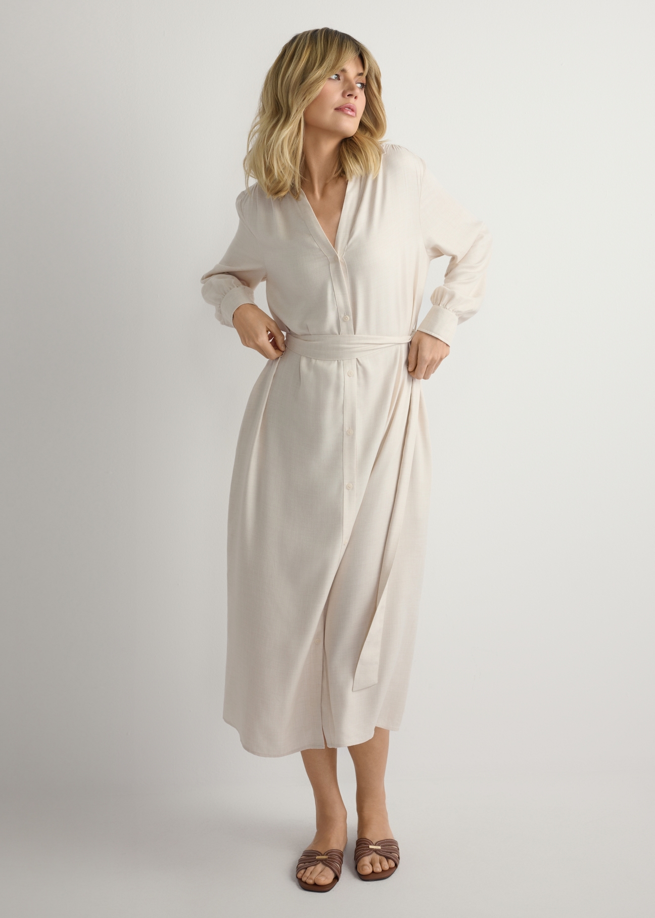 Jasnobeżowa sukienka damska midi SUKDT-0269-1A(W26), widok produktu z przodu na modelce. Widoczna połowa sylwetki.