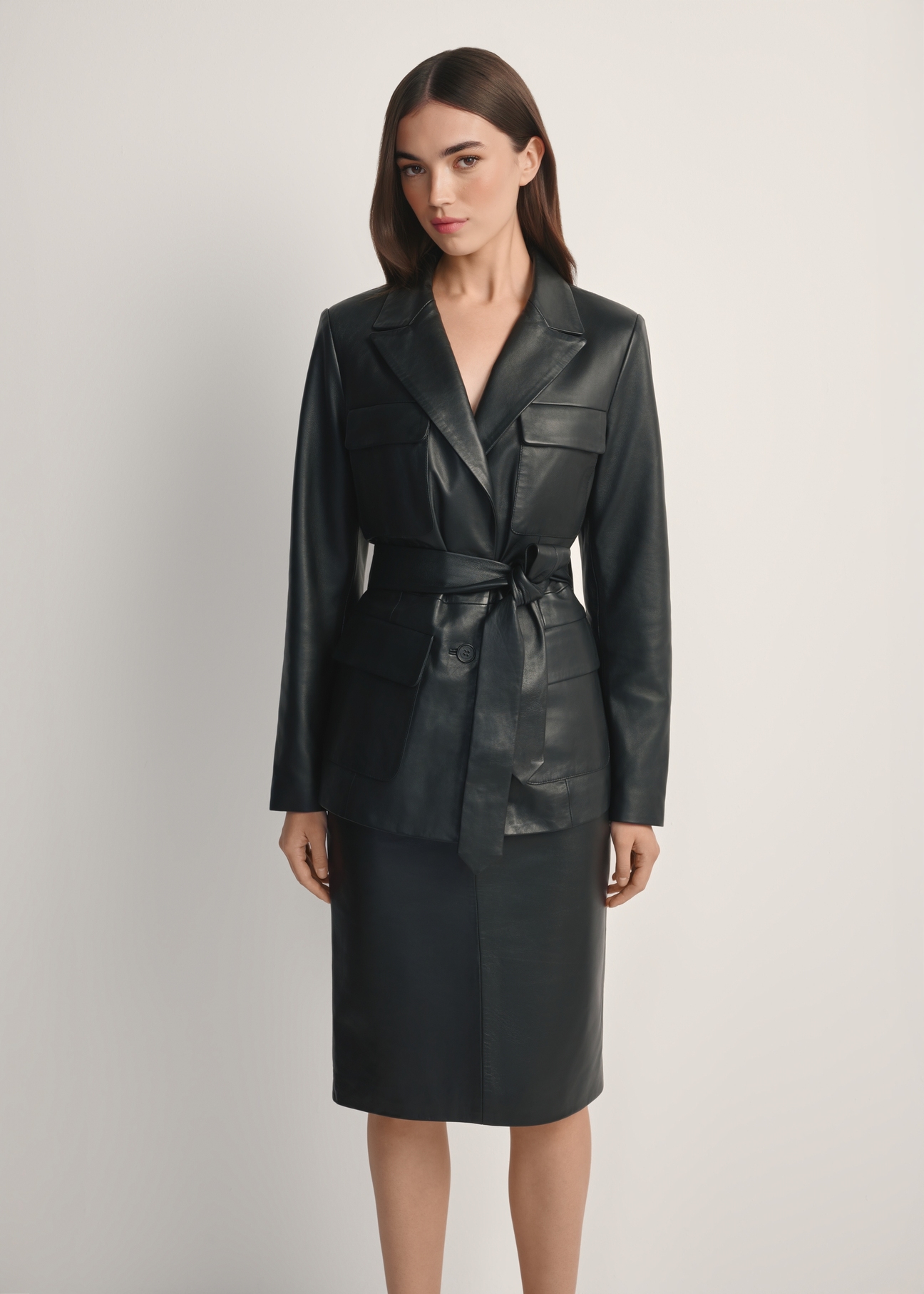 Czarna skórzana marynarka damska z paskiem KURDS-0545-99(W26), widok produktu z przodu na modelce. Widoczna połowa sylwetki.