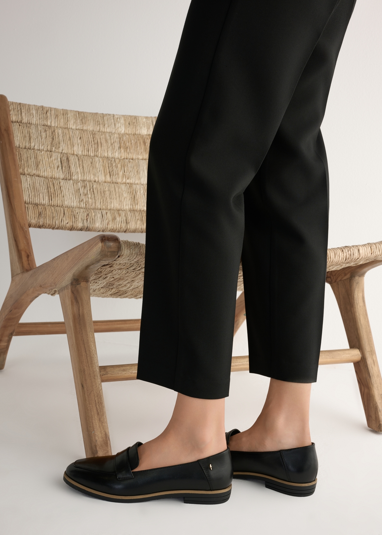 Skórzane czarne mokasyny damskie BUTYD-1067-99(W25), widok produktu od boku na modelce, widoczna połowa sylwetki.