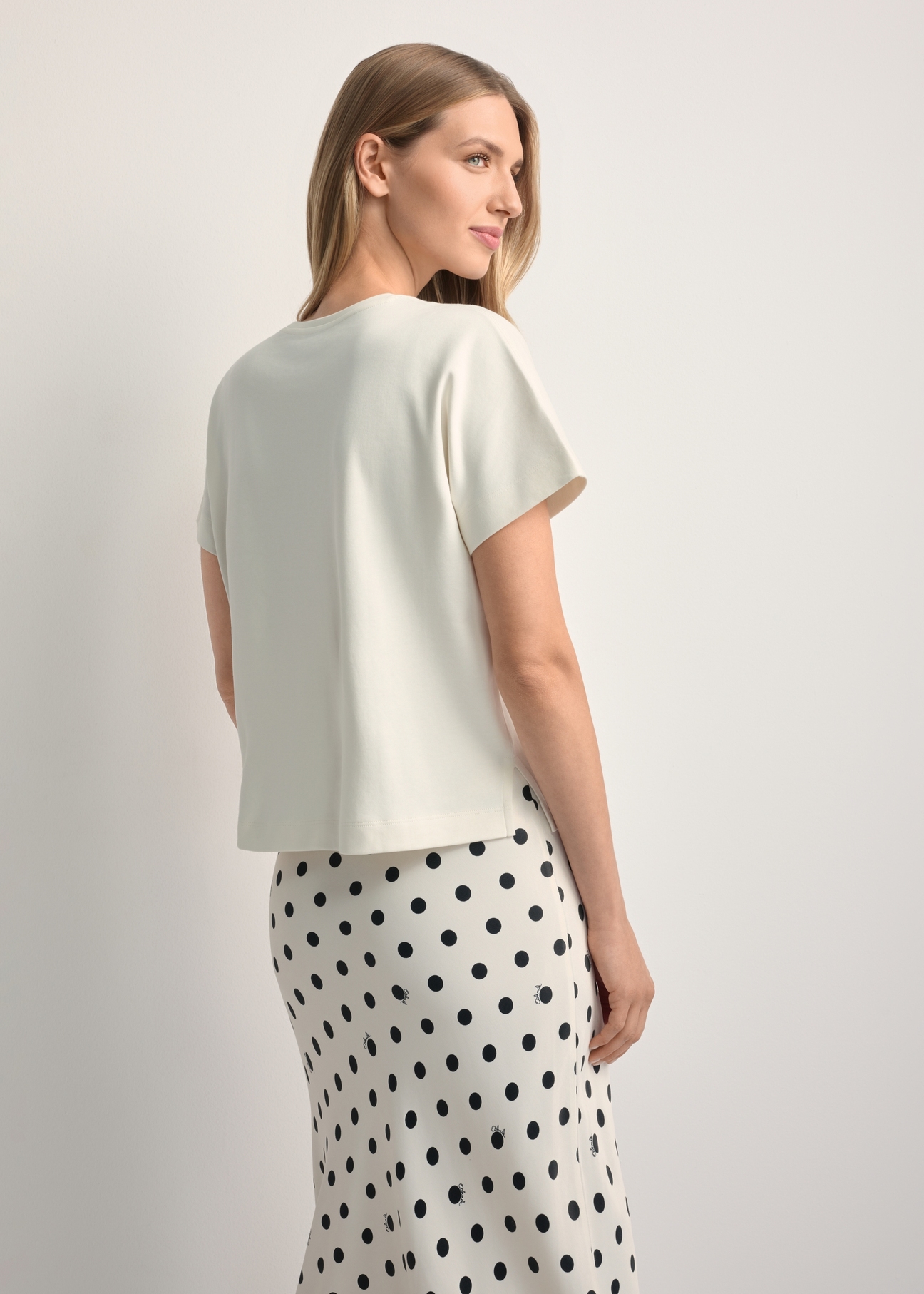 Kremowy t-shirt damski z bawełny merceryzowanej TSHDT-0154-0B(W26) - widok produktu z tyłu, na jasnym tle. Widoczna sylwetka do kolan. 