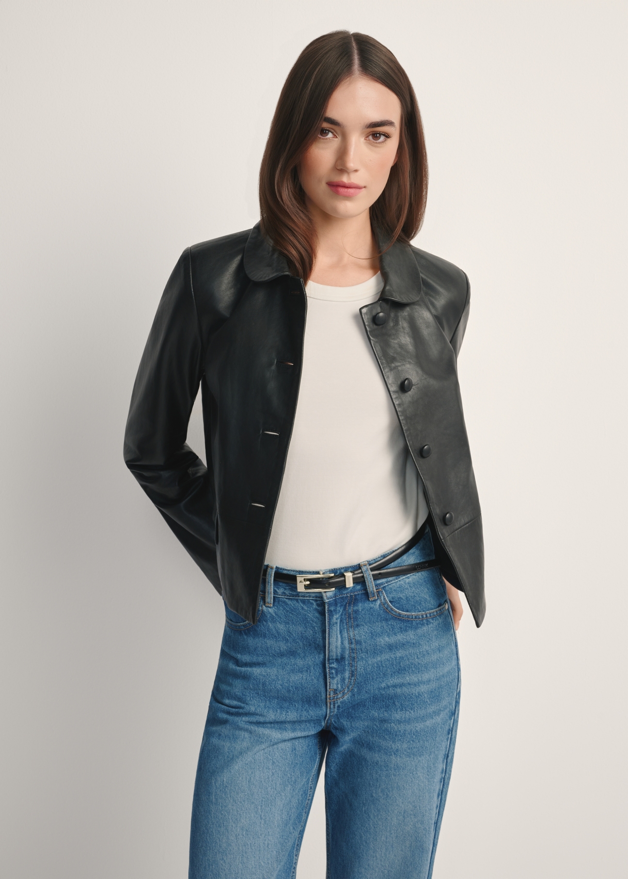 Czarna krótka skórzana kurtka damska KURDS-0598-99(W26), widok produktu od przodem na modelce, widoczna połowa sylwetki.