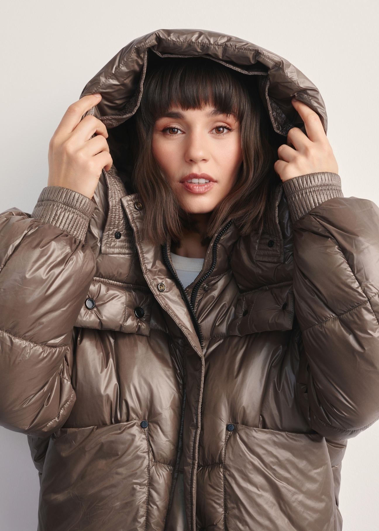 Krótka brązowa kurtka damska KURDT-0608-82(Z25), widok produktu z kapturem na modelce na jasnym tle.