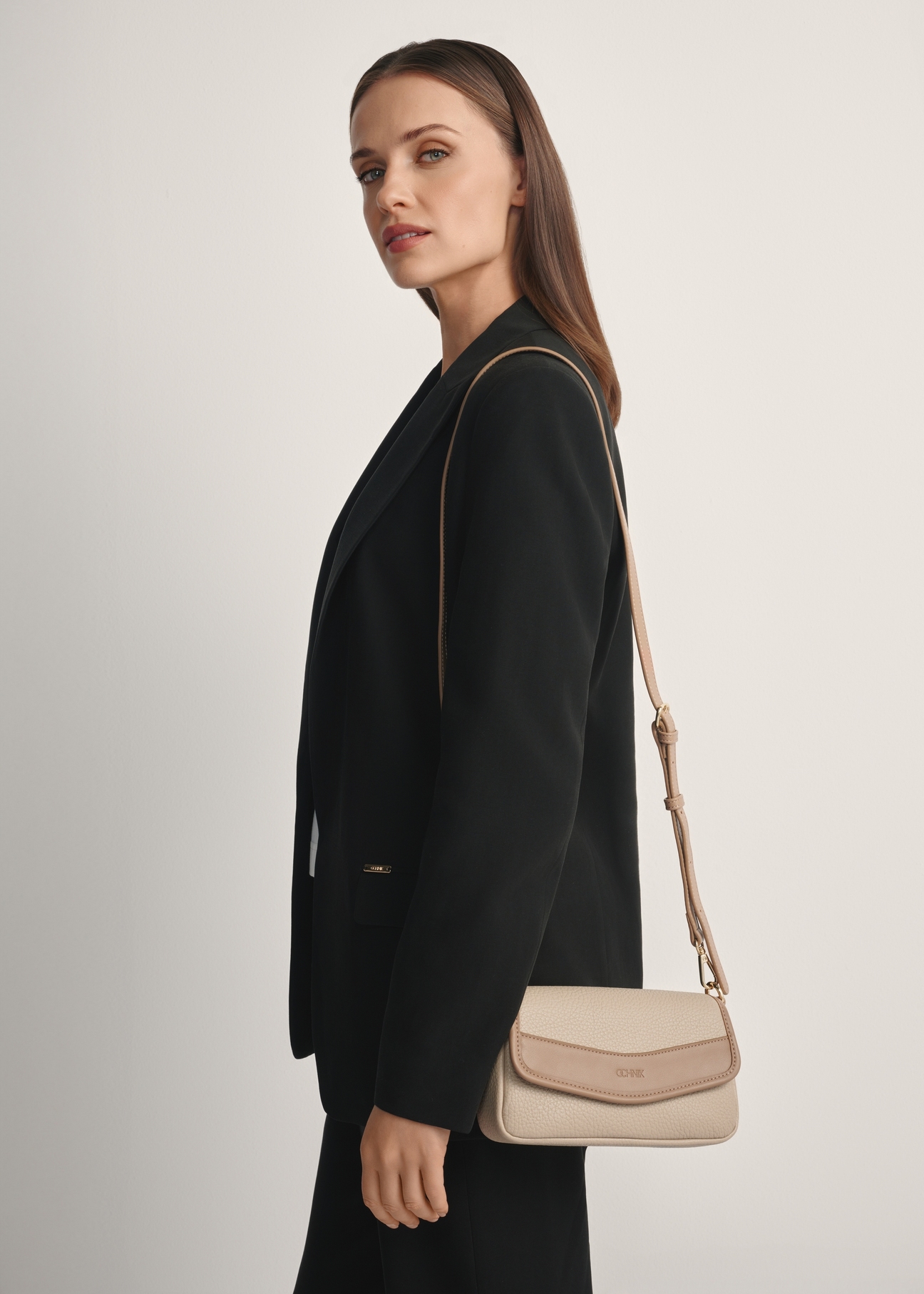 Mała torebka damska w kolorze beżu TOREC-1163-1D(W26), widok produktu od przodu na modelce, widoczna połowa sylwetki.