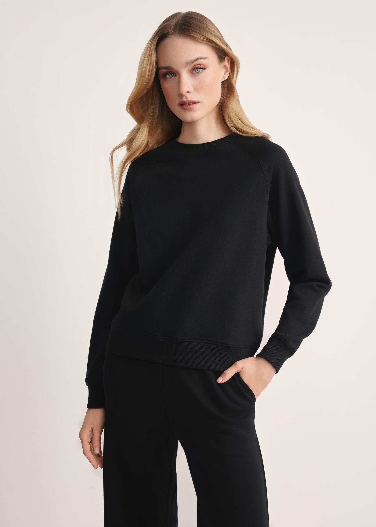 Czarna bluza damska BLZDT-0114-99(Z25), produkt widoczny od przodu na modelce, widoczne pół sylwetki.