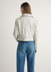 Skórzana ramoneska damska w kolorze kremowym KURDS-0585-0B(W26) - widok produktu z tyłu, na modelce, na jasnym tle. Widoczna połowa sylwetki. 