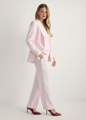 Marynarka damska w kolorze różowym ZAKDT-0031A-5A(W26), widok produktu z boku na modelce. Widoczna cała sylwetka.