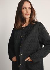 Czarna długa pikowana kurtka damska KURDT-0631-99(W26) - widok produktu z przodu na modelce, na białym tle. Widoczna połowa sylwetki. 