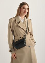 Czarna mała torebka damska na ramię TOREC-0916-99(W26) - widok produktu lekko po skosie, na modelce, na jasnym tle. Widoczna połowa sylwetki.