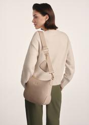Beżowa torebka damska w stylu hobo TOREC-0829A-80(Z25), widok produktu na ramieniu modelki. Widoczna połowa sylwetki.