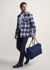 Granatowa torba podróżna TORMN-0382-69(Z25), widok produktu w dłoni modela. Widoczna cała sylwetka.