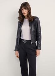 Czarna krótka kurtka skórzana damska KURDS-0294-99(KS), widok produktu z przodu na modelce. Widoczna połowa sylwetki.
