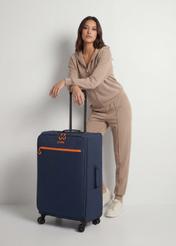 Walizka duża na kółkach WALNY-0045-7D-28(W26), widok produktu skosem obok sylwetki modelki.