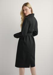 Długa czarna kurtka damska w formie płaszcza KURDT-0512-99(W25), widok produktu od tyłu na modelu, widoczna połowa sylwetki.