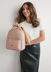 Różowy damski średni plecak TOREC-0920-5A(W26), widok produktu w dłoni modelki. Widoczna połowa sylwetki.