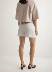 Białe spódnico-spodenki damskie SZODT-0008-0B(W26), widok produktu z tyłu na modelce. Widoczna połowa sylwetki.