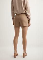 Damskie eleganckie szorty w kolorze camelu SZODT-0018-1D(W26), widok produktu z tyłu na modelce. Widoczna połowa sylwetki.