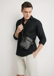 Ciemnobrązowa skórzana saszetka męska TORMS-0501-1I(W26) - widok produktu z przpodu, na modelu, na jasnym tle. Widoczna sylwetka do kolan.