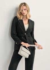 Kremowa mała torebka damska na ramię TOREC-0916-0B(W26), widok produktu z przodu w dłoni modelk. Widoczna połowa sylwetki.