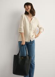 Czarna duża torebka damska shopper TOREC-1142-9I(W26), widok produktu w dłoni modelki. Widoczna cała sylwetka.