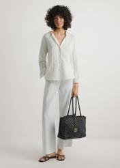 Ciemnobrązowa pleciona torebka damska TORES-1301-1I(W26), widok produktu w dłoni modelki. Widoczna cała sylwetka.