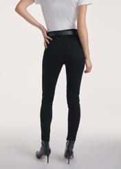 Czarne jeansowe spodnie damskie JEADT-0010A-99(Z25), produkt widoczny z tyłu na modelce, widoczne pół sylwetki.
