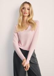 Jasnoróżowy sweter damski SWEDT-0250-34(Z25), widok produktu z przodu na modelce. Widoczna połowa sylwetki.