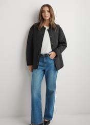 Czarna pikowana kurtka damska KURDT-0580-99(W26) - widok produktu z przodu, na modelce, na jasnym tle. Widoczna cała sylwetka.