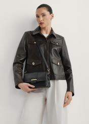 Skórzana torebka damska w kolorze czarnym TORES-1220-9I(W26) - widok torebki z przodu, na modelce, na jasnym tle. Widoczna sylwetka do kolan. 