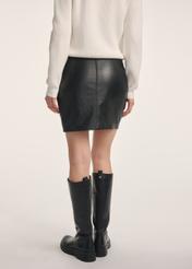 Czarna skórzana spódnica mini SPCDS-0079-3206(Z25) - widok produktu z tyłu na modelce na białym tle. Widoczna połowa sylwetki. 