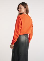 Pomarańczowa bluza damska BLZDT-0114-30(Z25) - widok produktu z tyłu na modelce na białym tle. Widoczna sylwetka do kolan. 