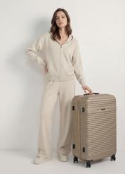 Walizka duża na kółkach WALAB-0040-2X-28(W26), widok produktu skosem przy modelce, widoczna cała sylwetka.