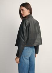 Czarna krótka skórzana kurtka damska KURDS-0598-99(W26), widok produktu od tyłu na modelce, widoczna połowa sylwetki.