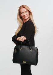 Czarna damska torba na laptopa TOREC-0978A-99(Z25) - widok produktu z przodu na modelce na białym tle. Widoczna sylwetka do kolan, bokiem.