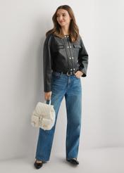 Kremowy pikowany plecak damski TOREC-1195-0A(W26) - widok produktu z przodu, trzymanego przez modelkę w ręku, na jasnym tle. Widoczna cała sylwetka. 