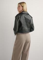 Krótka skórzana ramoneska damska KURDS-0434-99(W26) - widok produktu z tyłu, na modelce, na jasnym tle. Widoczna sylwetka do kolan.