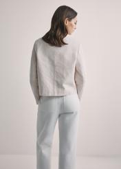 Jasnobeżowa kurtka damska z lnem KURDT-0652-1A(W26), widok produktu z tyłu na modelce. Widoczna połowa sylwetki.