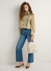 Kremowy damski średni plecak TOREC-0920-0B(W26), widok produktu w dłoni modelki. Widoczna cała sylwetka.