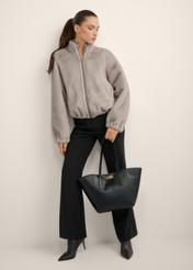 Czarna torebka damska typu shopper TOREC-1375-99(Z26), widok produktu w dłoni modelki. Widoczna cała sylwetka.