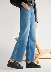 Wysokie czarne skórzane tenisówki damskie BUTYD-1062-99(W26) - widok produktu z boku, na modelce, na jasnym tle. Widoczna sylwetka do kolan. 