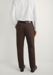 Brązowe spodnie męskie SPOMT-0121-1I(W26) - widok produktu z tyłu na modelu, na jasnym tle. Widoczna połowa sylwetki. 