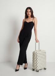 Mała walizka w kropki na kółkach WALAB-0074-0P-19(W26), widok produktu skosem obok sylwetki modelki.