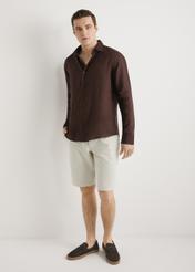 Brązowa lniana koszula męska KOSMT-0321A-1I(W26) - widok produktu z przodu, na modelu, na jasnym tle. Widoczna cała sylwetka. 
